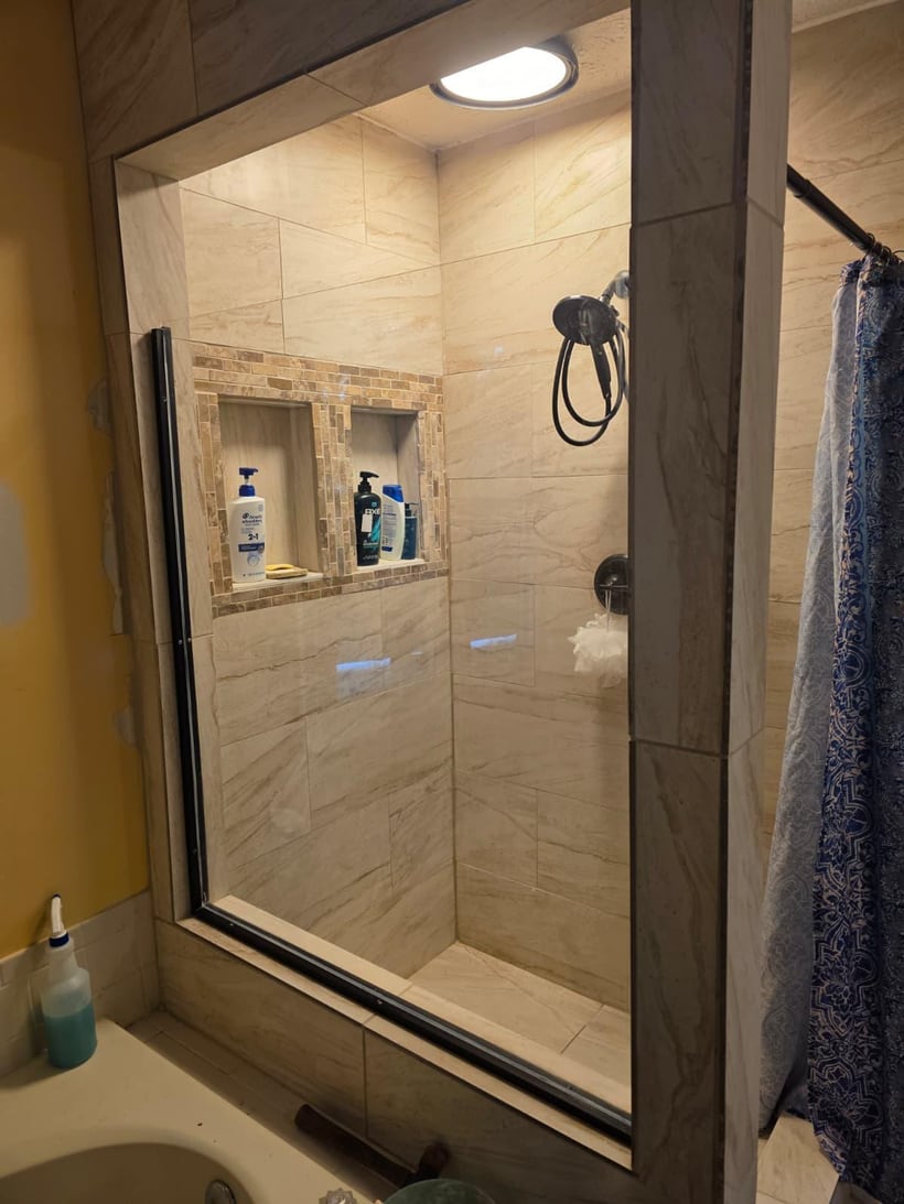 Finished tile shower remodel with warm wall tile, niche, and glass enclosure