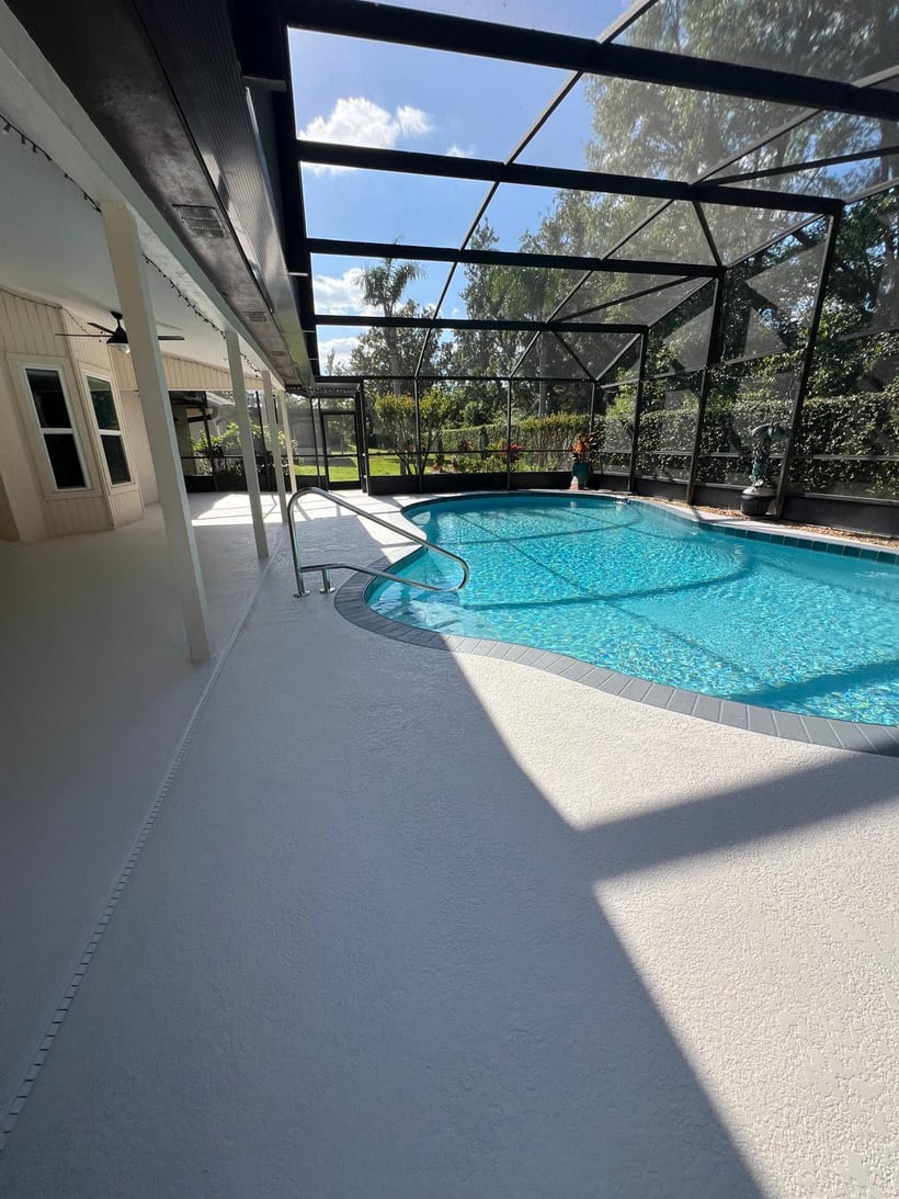 Finished pool deck coating around a screened backyard pool area