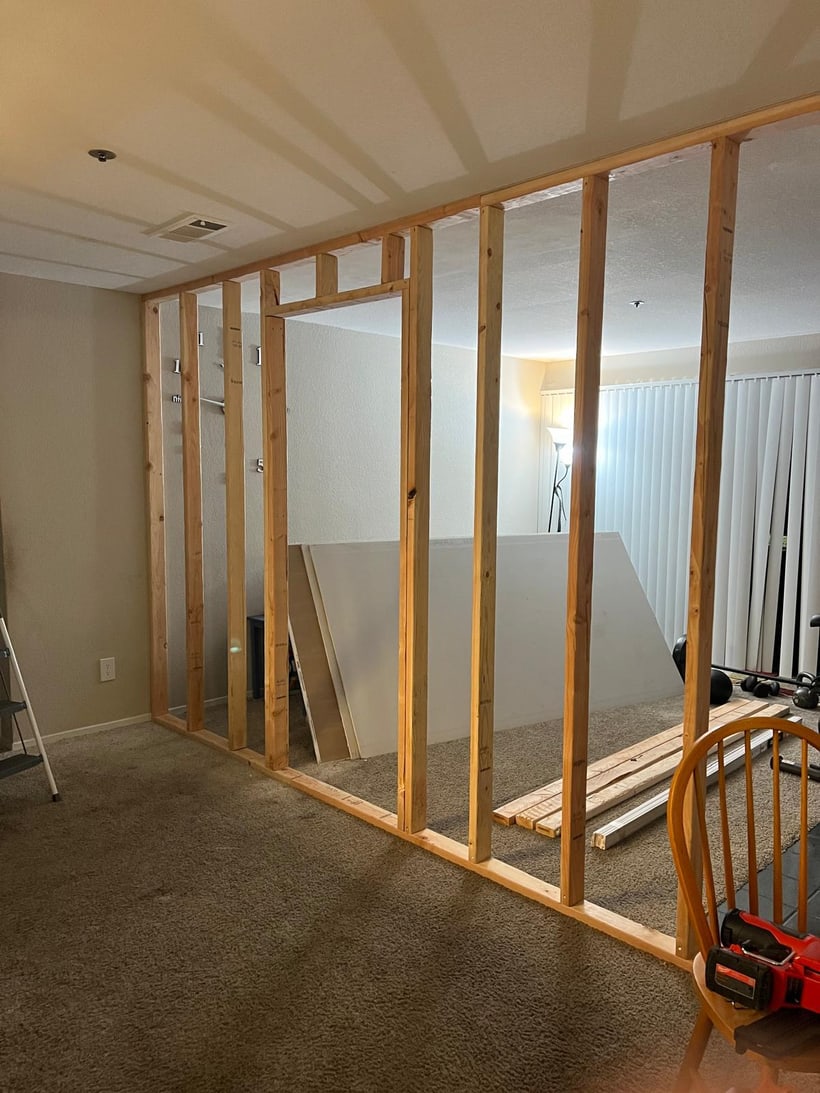 Interior room addition framing with exposed wood studs and drywall preparation inside a home